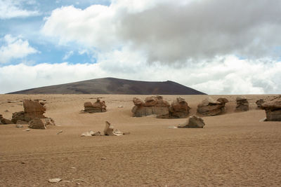 Scenic view of rocky mountains in front of sea against cloudy sky