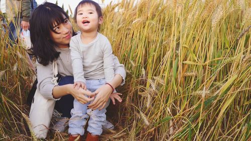 Happy mother and daughter standing on field