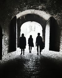 Silhouette people walking in tunnel