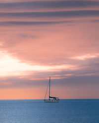 Sailboat sailing on sea against sky during sunset