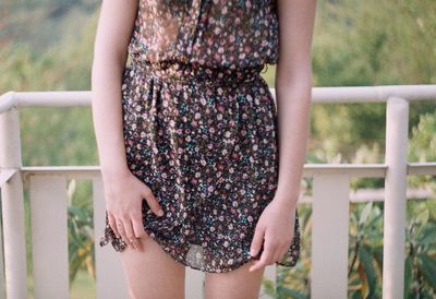 Midsection of young woman standing against railing in balcony