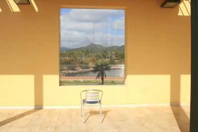 Empty chairs and table against window