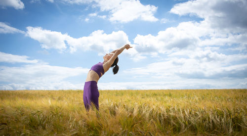 Woman exercising and doing a stretch in the middle of a field. workout outdoors.