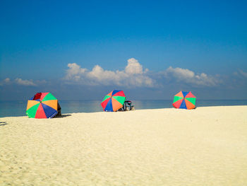 Deck chairs on beach against blue sky