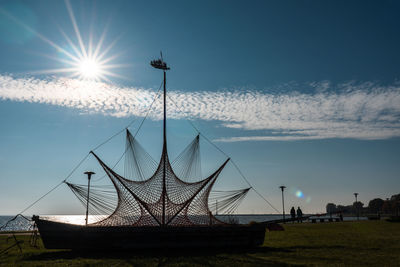 An art installation of a sail boat against the sky and shining sun