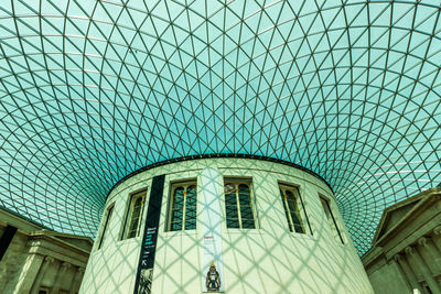 Low angle view of glass building against blue sky