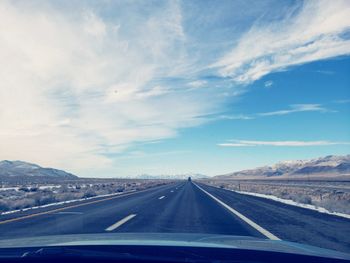 Road leading towards mountains against sky