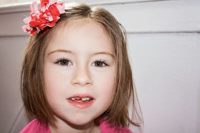 Close-up portrait of cute girl against wall