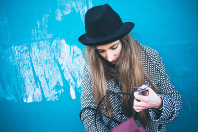 Beautiful woman wearing hat against blue wall