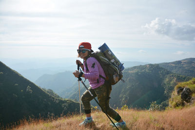 Woman with hiking poles on landscape against sky