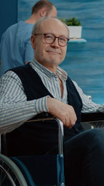 Portrait of senior man sitting on wheelchair at hospital