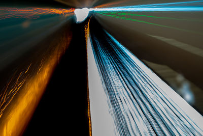 Low angle view of light trails on bridge against sky at night