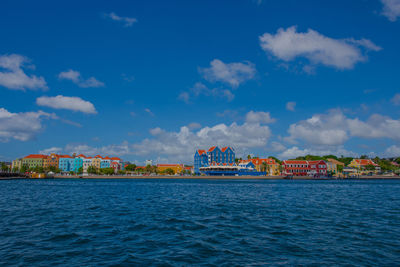 Scenic view of sea by buildings against blue sky