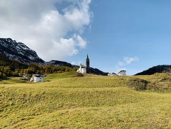 Scenic view of field by buildings against sky