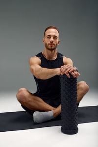 Portrait of young man exercising against black background