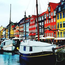 Boats moored at harbor against sky in city