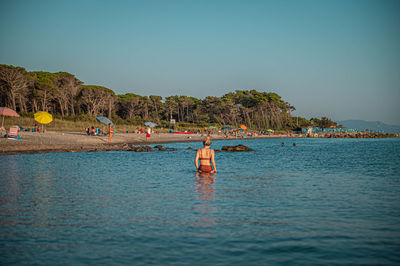 People in sea against clear sky