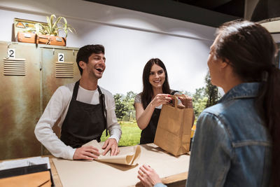 Happy colleagues selling merchandise to female customer at store