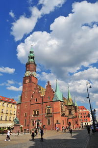 People walking in front of historical building against sky