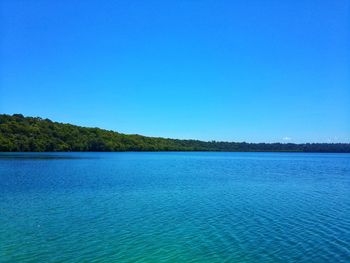 Scenic view of lake against clear blue sky