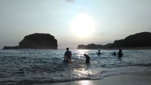 Silhouette people on beach against sky during sunset