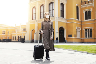 Full length portrait of a woman standing in front of building