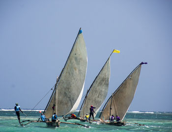 People sailing boats in sea against clear sky