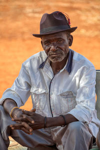 Portrait of man wearing hat sitting outdoors