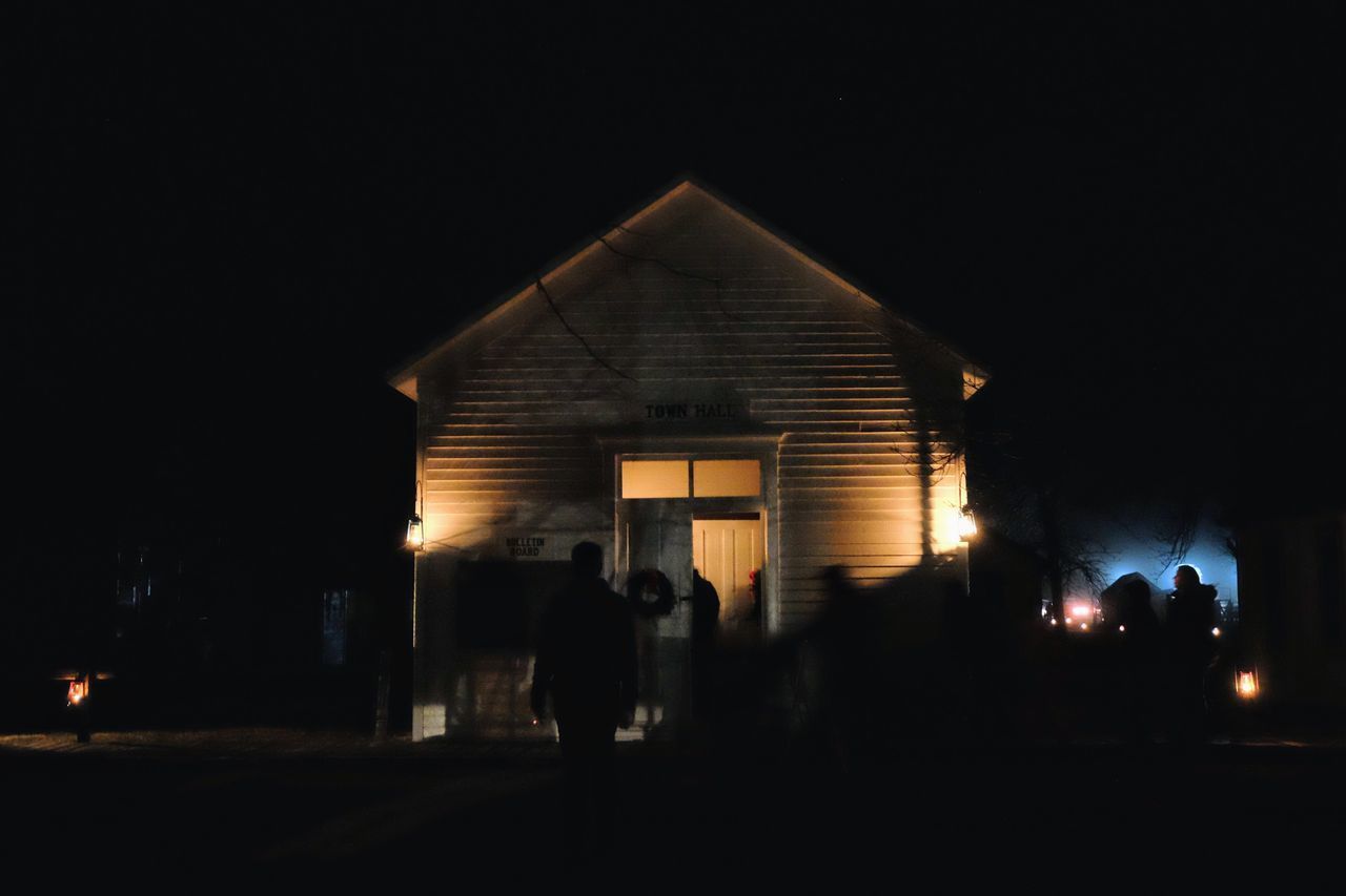 SILHOUETTE PEOPLE IN ILLUMINATED BUILDING