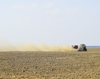 Vehicle moving on field against sky