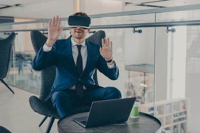 Full length of man using mobile phone while sitting in office