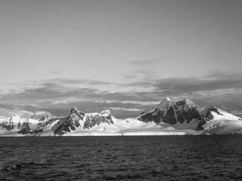 Black and white photo of sea against snowcapped mountains in antarctica