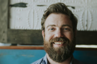 Close-up portrait of happy man with beard sitting at home