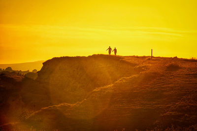 Silhouette person on land against sky during sunset