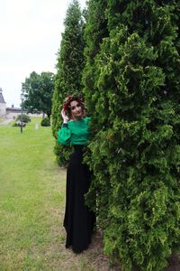 Portrait of woman wearing wreath while standing by trees