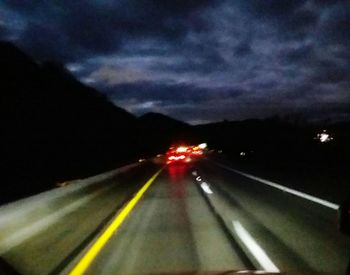 Light trails on road against sky at night