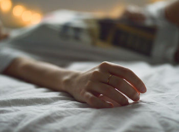 Close-up of human hand on bed