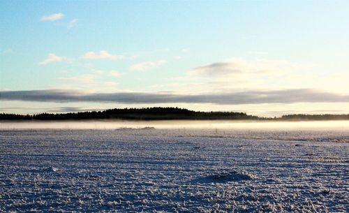 Scenic view of frozen landscape against sky during winter