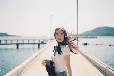Portrait of girl standing on beach against sky