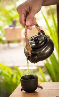 Cropped hand of person pouring water on table