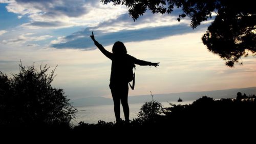 Silhouette man standing by tree against sky during sunset