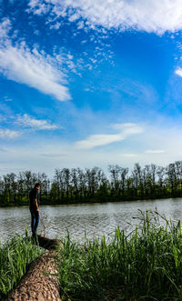 Woman standing by lake against sky