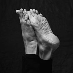 Black and white close-up of human feet against black background