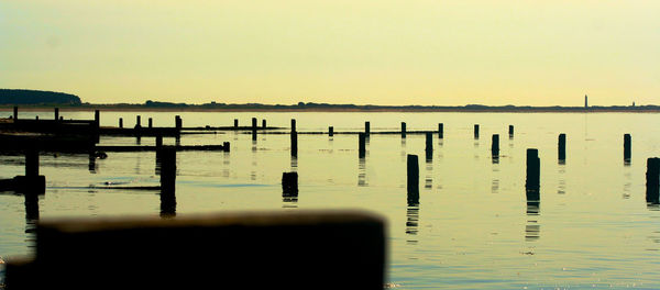 View of pier in sea at sunset