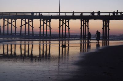 Silhouette people standing on beach against sky during sunset