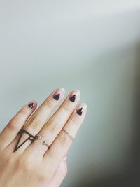 Cropped hand of woman with painted nails against wall