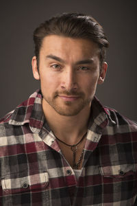 Close-up portrait of confident young man against gray background