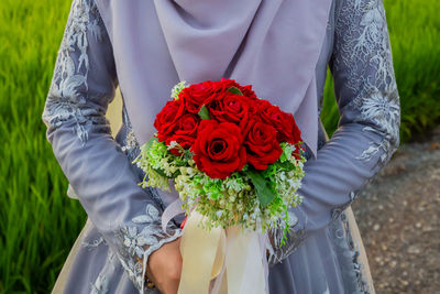 Midsection of bride holding bouquet