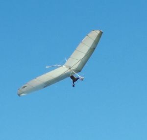 Low angle view of airplane flying against clear blue sky