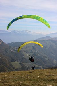 People paragliding over mountain against sky